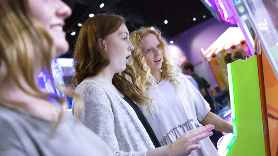 A group of girls play arcade games