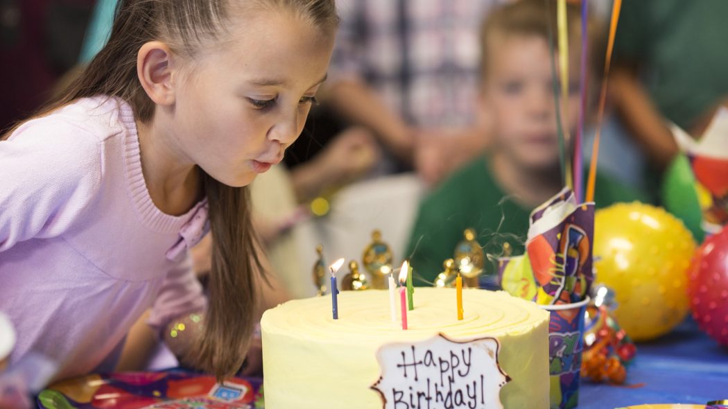 Girl blowing out birthday candles on cake.