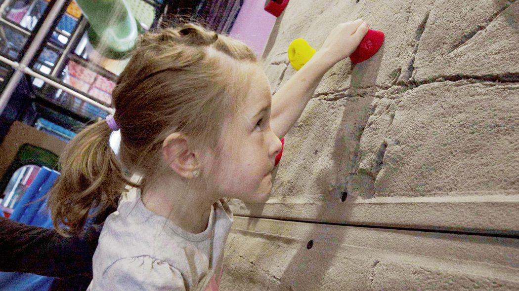 Girl climbing on indoor climbing wall.
